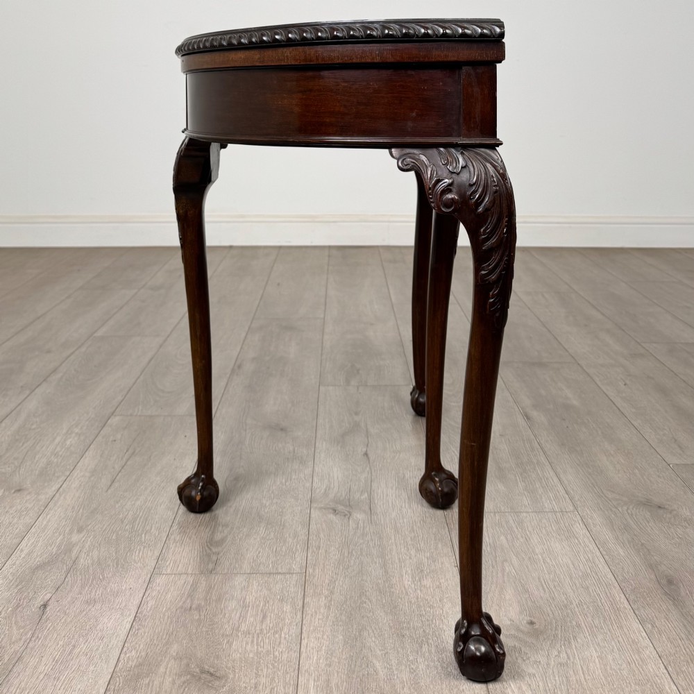 A circular dark mahogany card table featuring acanthus carved knees and cabriole legs terminating in ball and claw feet. View III