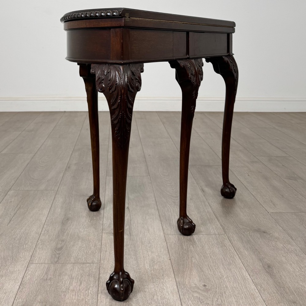 A circular dark mahogany card table featuring acanthus carved knees and cabriole legs terminating in ball and claw feet. View V