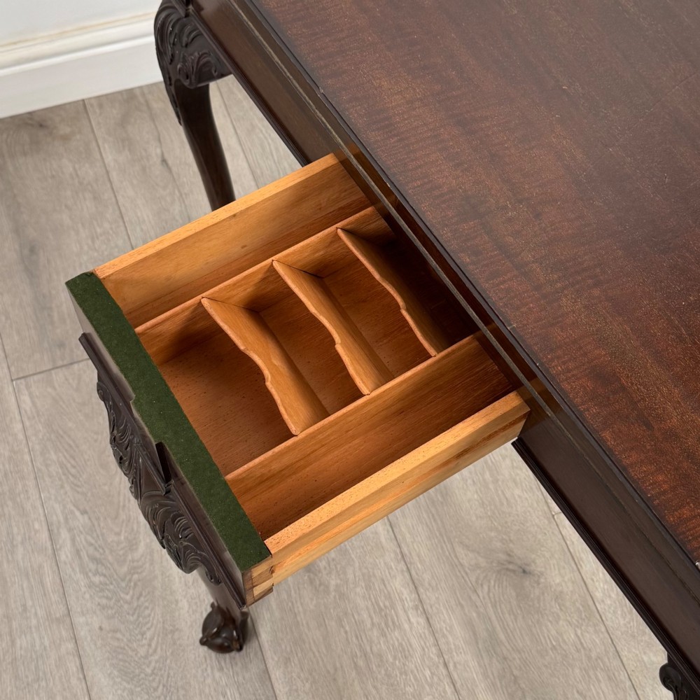 A circular dark mahogany card table featuring acanthus carved knees and cabriole legs terminating in ball and claw feet. View XII