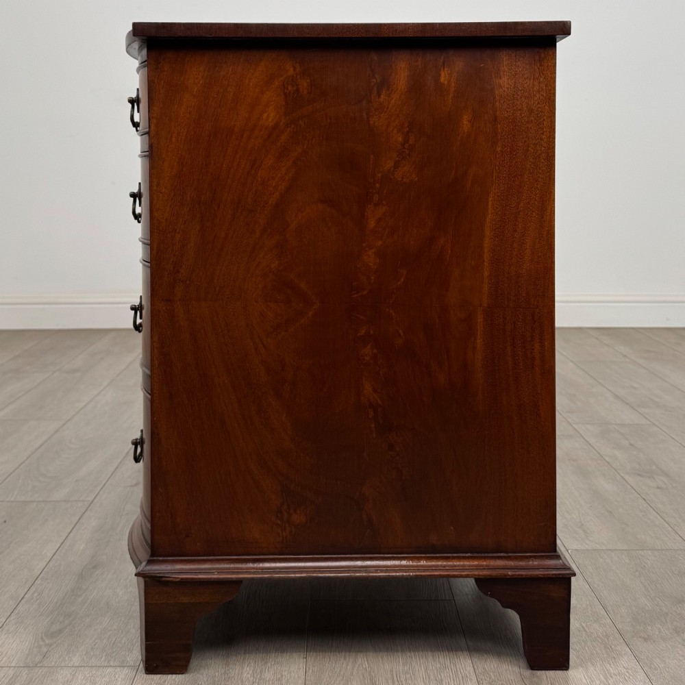 A twentieth-century mahogany kneehole desk featuring a serpentine front, multiple drawers with brass swan-neck handles, and bracket feet. View III