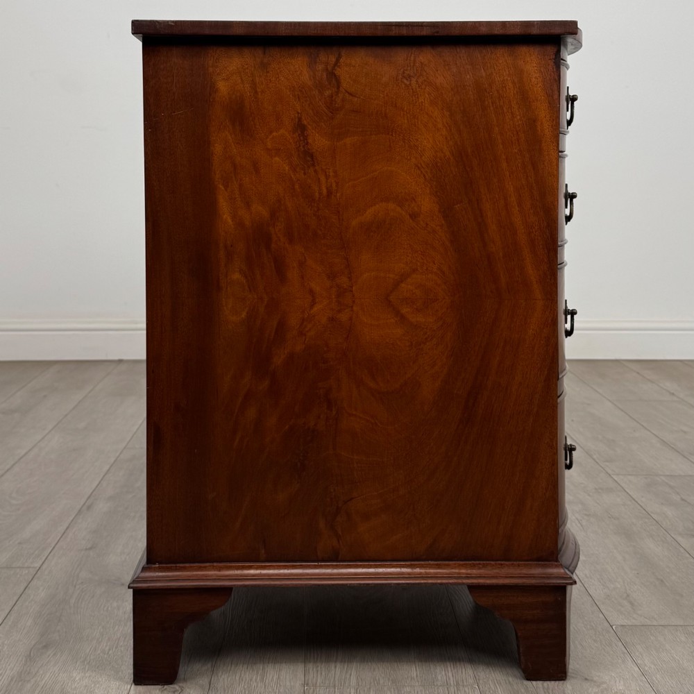 A twentieth-century mahogany kneehole desk featuring a serpentine front, multiple drawers with brass swan-neck handles, and bracket feet. View VII