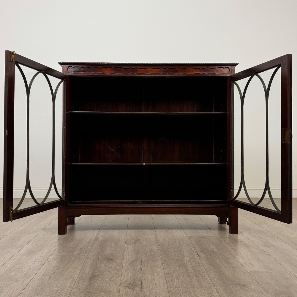 An Edwardian dark mahogany display cabinet featuring two glass doors with interlaced astragal glazing bars and internal wooden shelves. View II