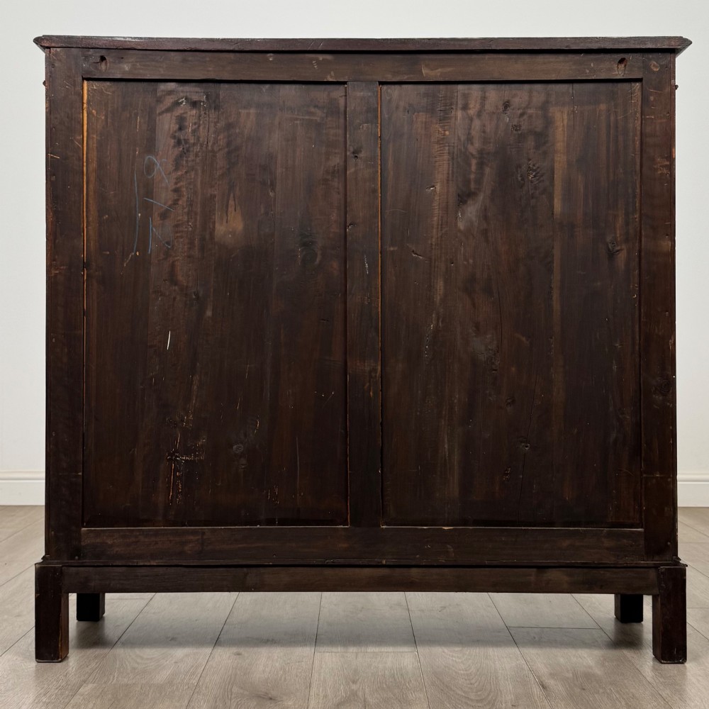 An Edwardian dark mahogany display cabinet featuring two glass doors with interlaced astragal glazing bars and internal wooden shelves. View VI