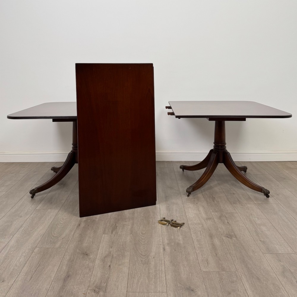 A 20th-century mahogany twin pedestal dining table featuring an extension leaf, reeded edges, and splayed quadruped feet with brass castors. View IV