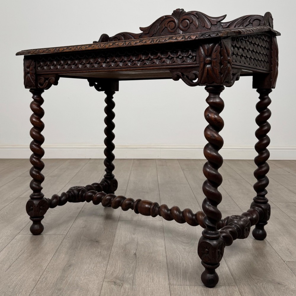 A 19th-century dark oak writing table featuring barley twist legs, carved stretchers, and an ornate carved cresting rail along the top gallery. View II