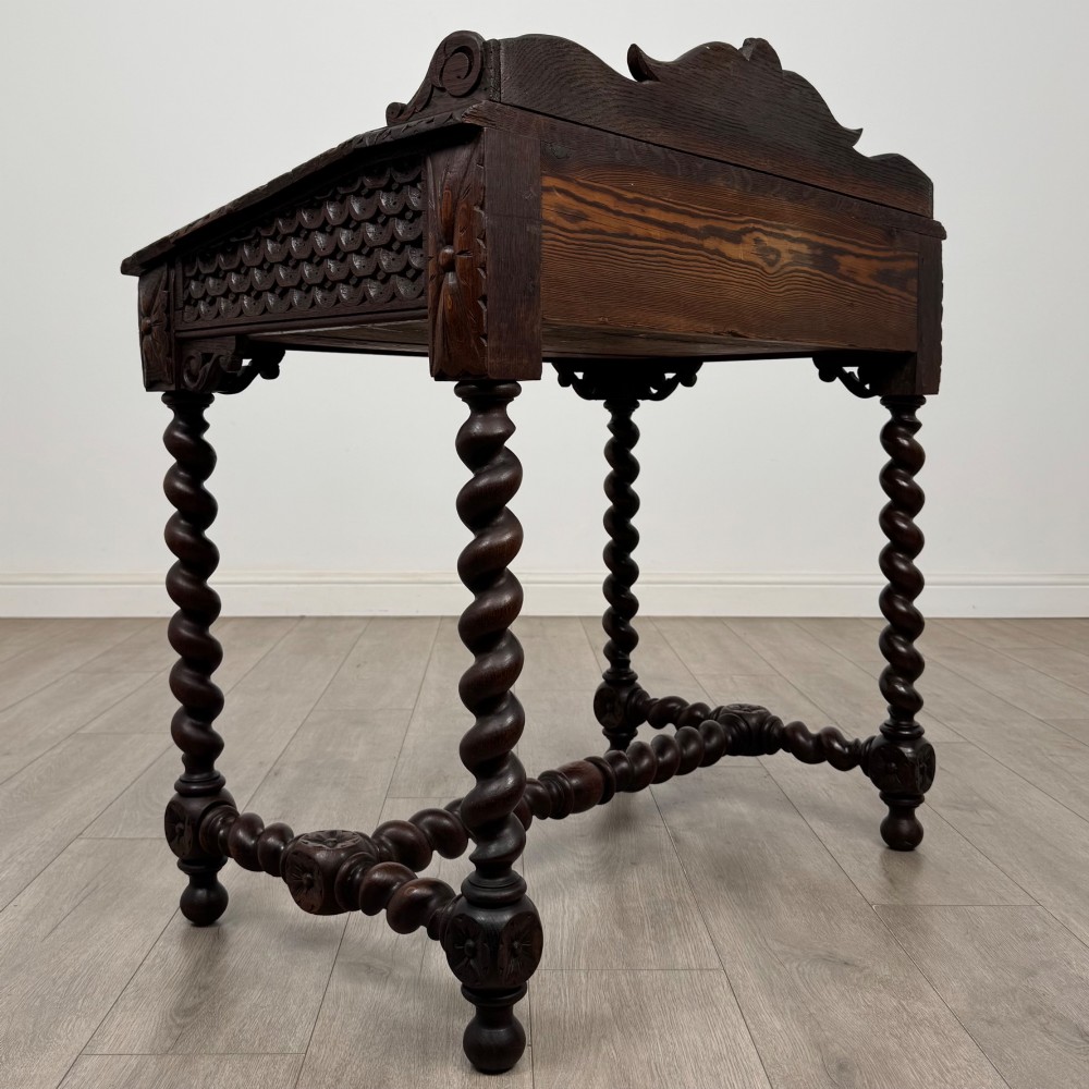 A 19th-century dark oak writing table featuring barley twist legs, carved stretchers, and an ornate carved cresting rail along the top gallery. View IV