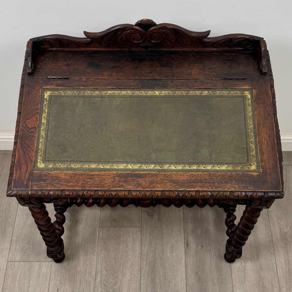 A 19th-century dark oak writing table featuring barley twist legs, carved stretchers, and an ornate carved cresting rail along the top gallery. View IX