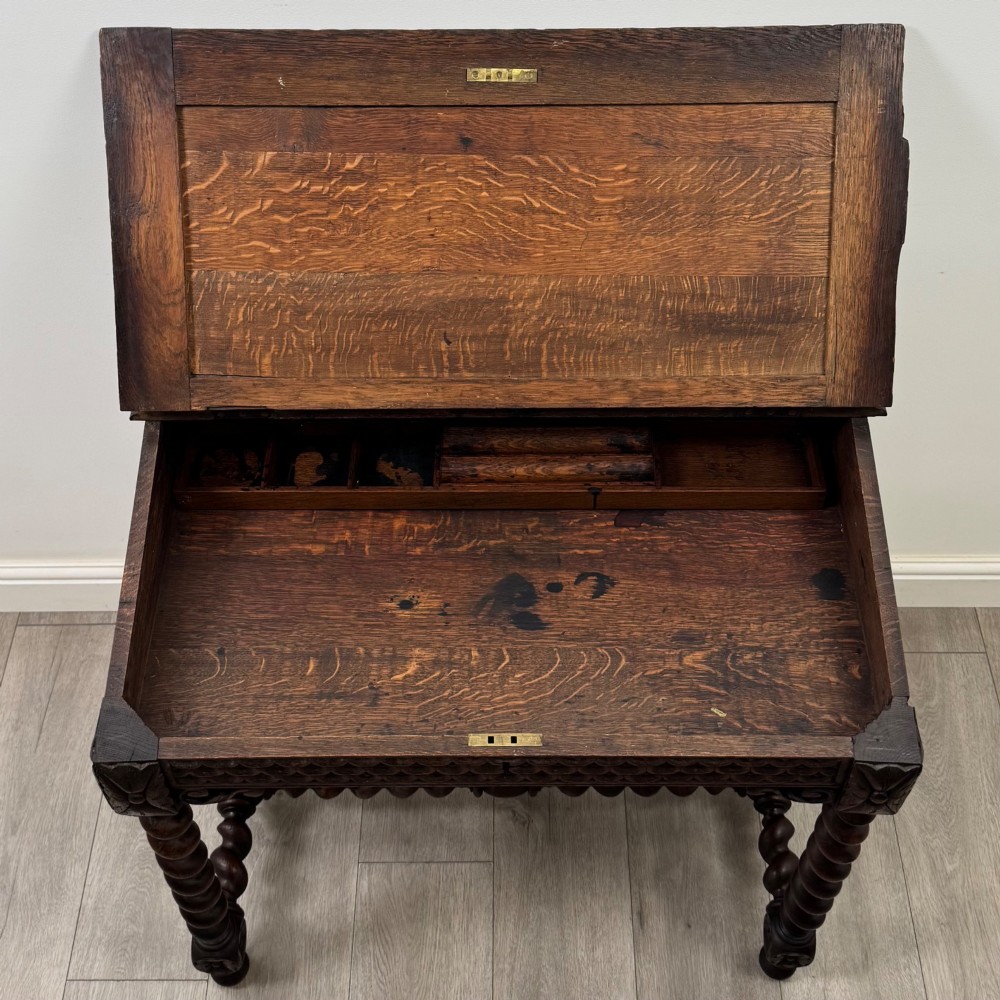 A 19th-century dark oak writing table featuring barley twist legs, carved stretchers, and an ornate carved cresting rail along the top gallery. View X