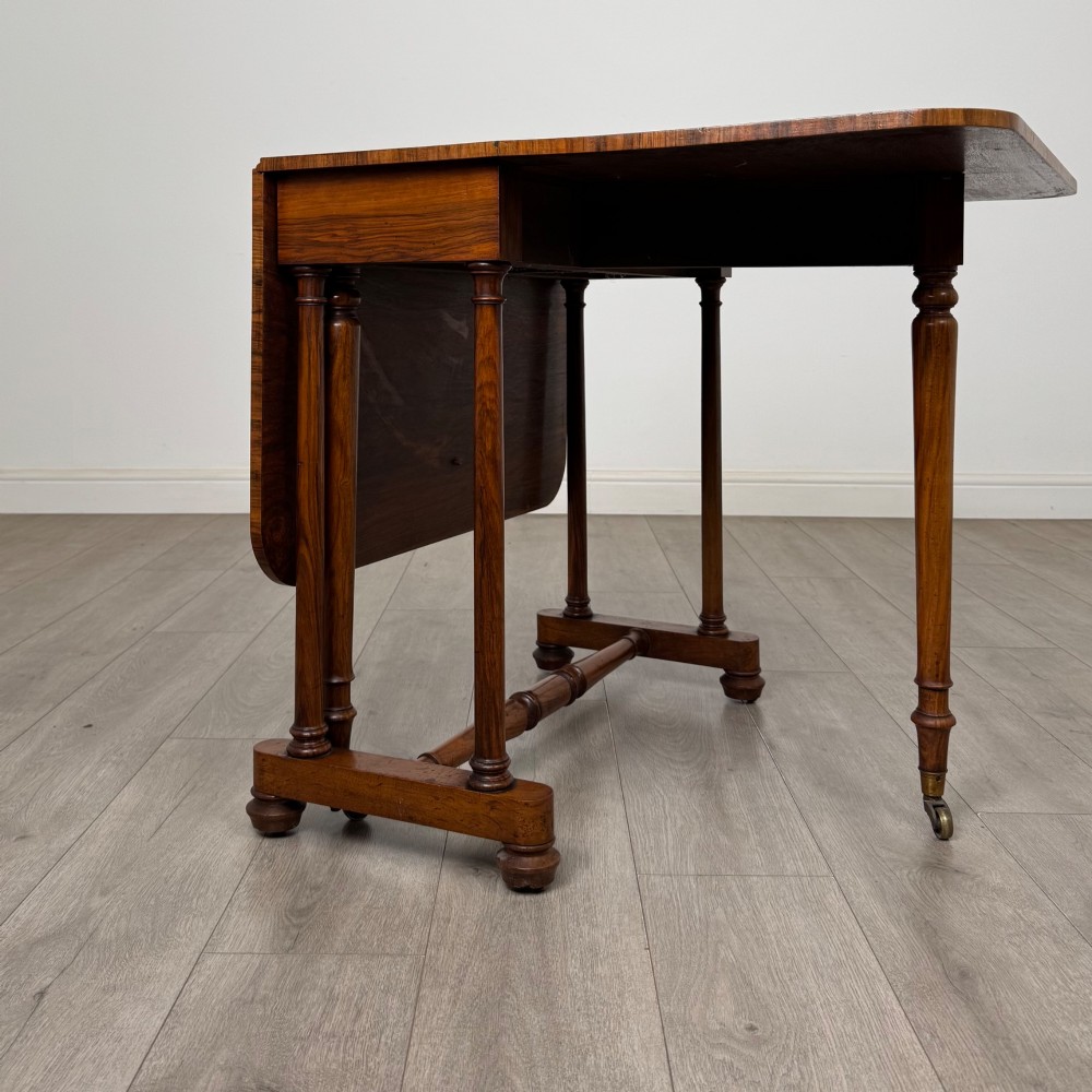 A 19th-century Victorian Sutherland table crafted from burr walnut with two folded drop leaves, turned supports, and brass castors. View II