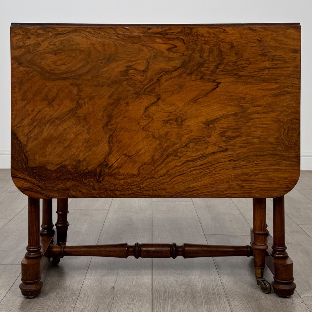 A 19th-century Victorian Sutherland table crafted from burr walnut with two folded drop leaves, turned supports, and brass castors. View III
