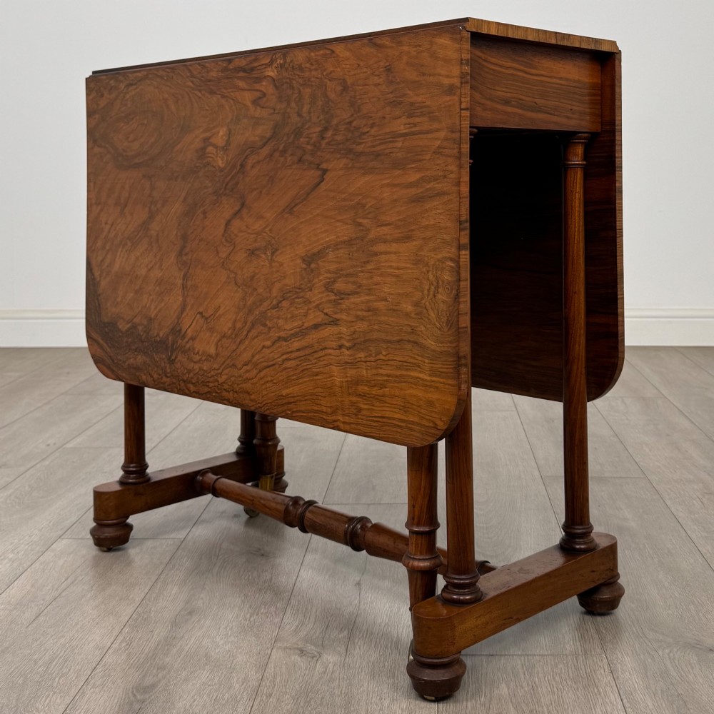 A 19th-century Victorian Sutherland table crafted from burr walnut with two folded drop leaves, turned supports, and brass castors. View IV