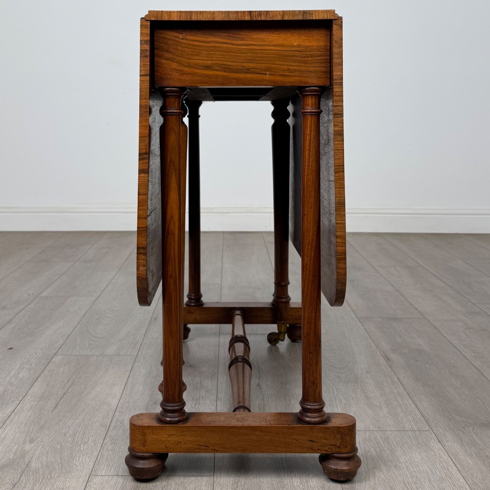 A 19th-century Victorian Sutherland table crafted from burr walnut with two folded drop leaves, turned supports, and brass castors. View V