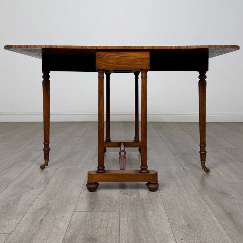 A 19th-century Victorian Sutherland table crafted from burr walnut with two folded drop leaves, turned supports, and brass castors. View VI