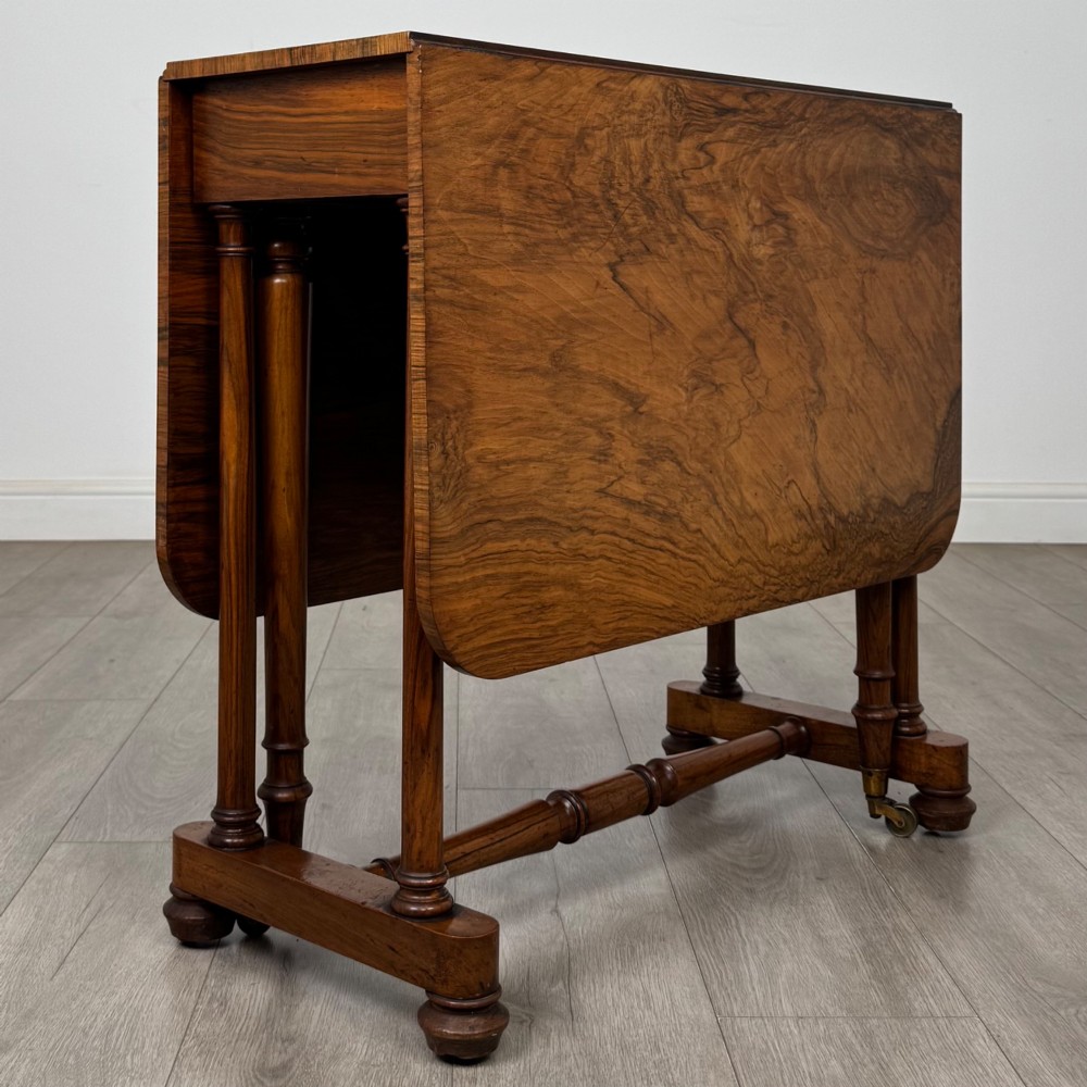 A 19th-century Victorian Sutherland table crafted from burr walnut with two folded drop leaves, turned supports, and brass castors. View VII