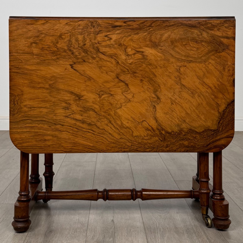 A 19th-century Victorian Sutherland table crafted from burr walnut with two folded drop leaves, turned supports, and brass castors. View VIII