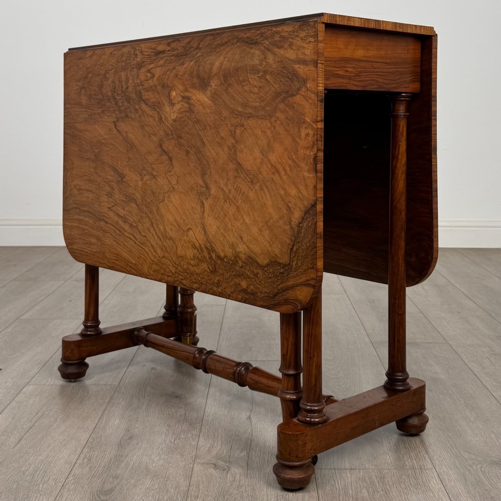 A 19th-century Victorian Sutherland table crafted from burr walnut with two folded drop leaves, turned supports, and brass castors. View IX