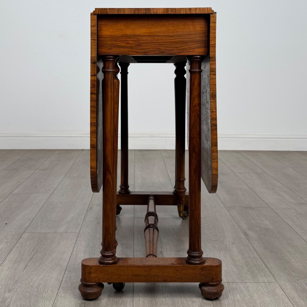 A 19th-century Victorian Sutherland table crafted from burr walnut with two folded drop leaves, turned supports, and brass castors. View X