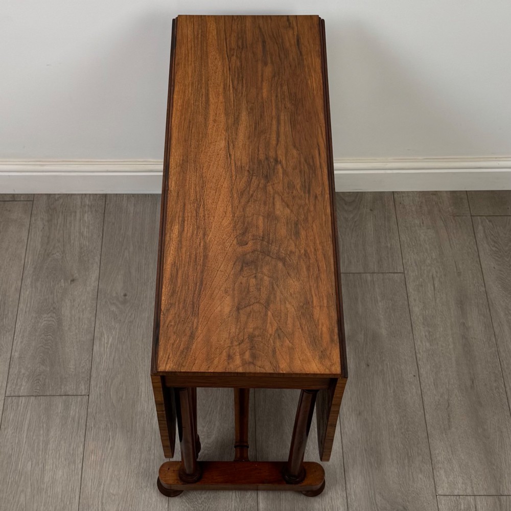A 19th-century Victorian Sutherland table crafted from burr walnut with two folded drop leaves, turned supports, and brass castors. View XI