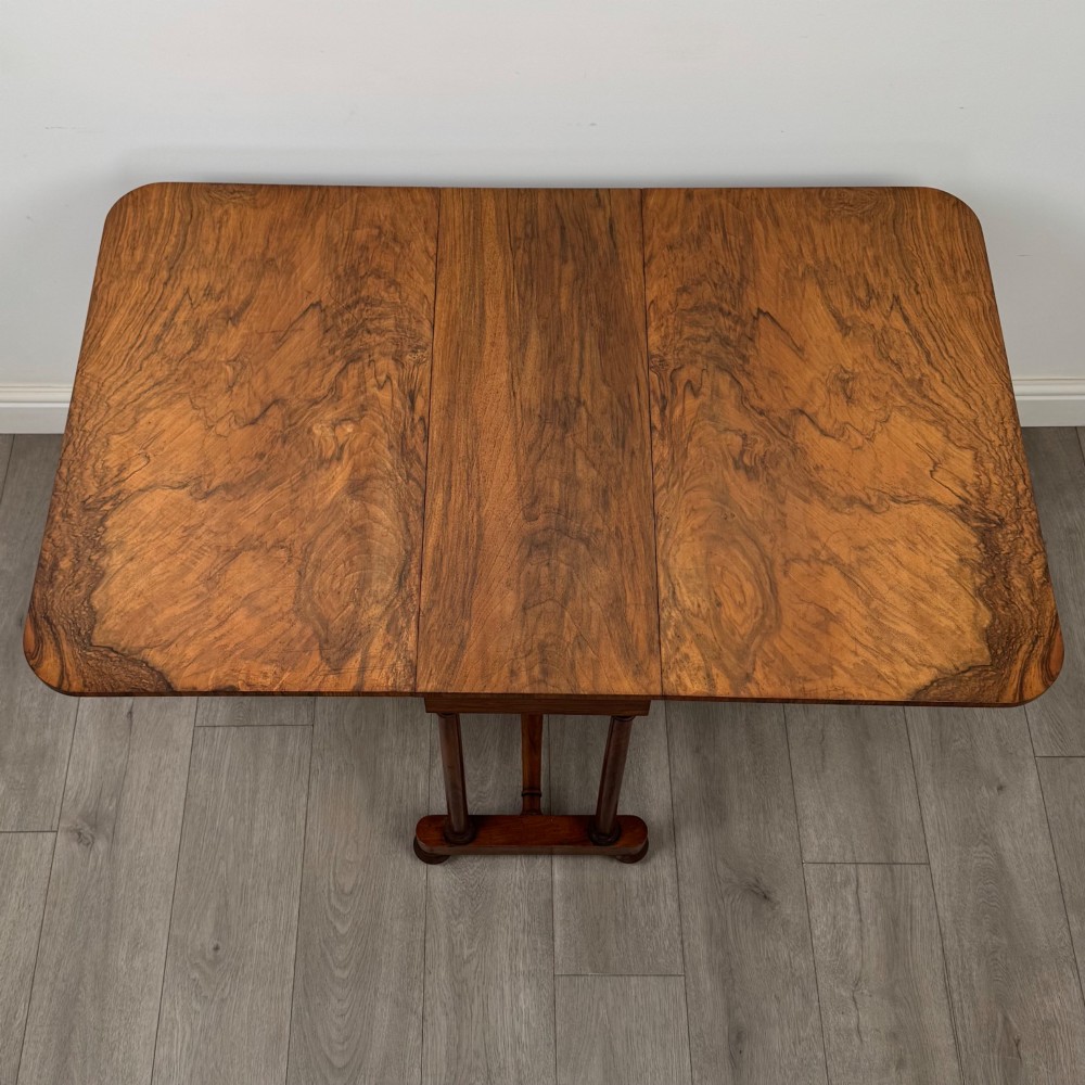 A 19th-century Victorian Sutherland table crafted from burr walnut with two folded drop leaves, turned supports, and brass castors. View XII