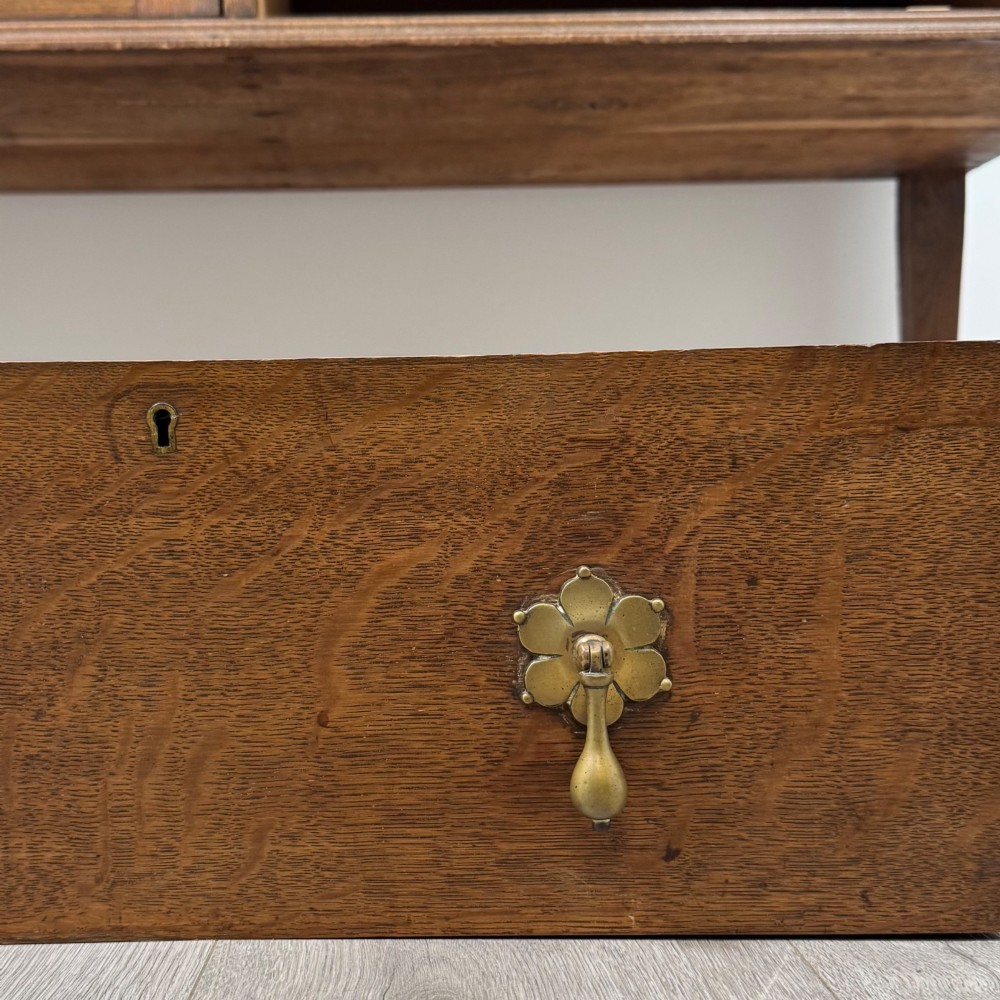 An Edwardian oak sideboard featuring a raised gallery back with a central circular mirror, a left cupboard door, two right drawers, and brass drop handles. View XII