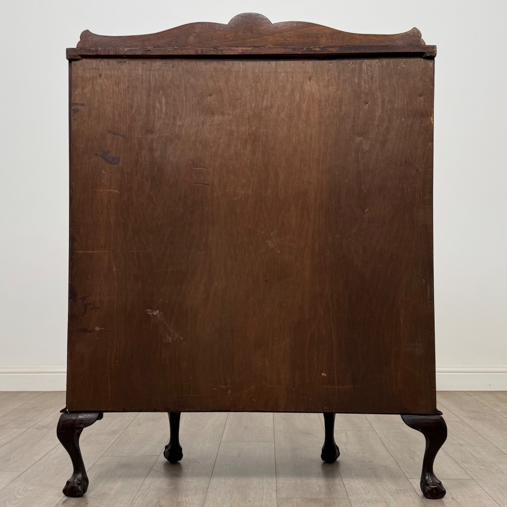 An Edwardian dark mahogany demi-lune display cabinet featuring glazed curved panels, a carved Greek key frieze, glass internal shelves, and cabriole legs with ball-and-claw feet. View V