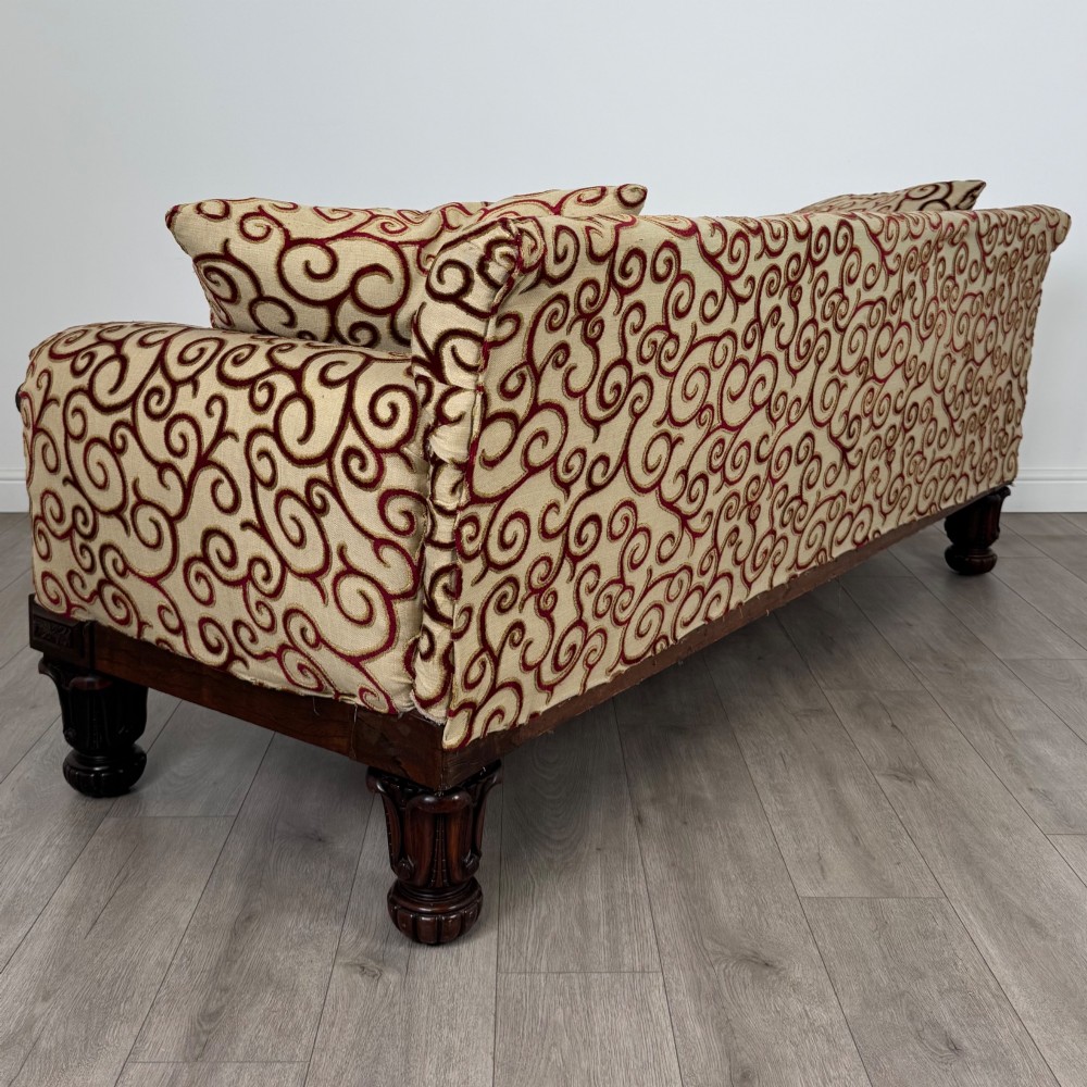 A 19th-century William IV sofa crafted from dark rosewood with carved scroll arms, turned legs, and swirl-patterned cream and burgundy fabric upholstery. View IV