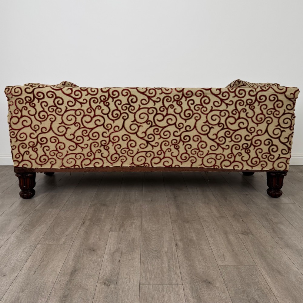 A 19th-century William IV sofa crafted from dark rosewood with carved scroll arms, turned legs, and swirl-patterned cream and burgundy fabric upholstery. View V