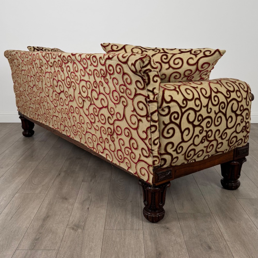 A 19th-century William IV sofa crafted from dark rosewood with carved scroll arms, turned legs, and swirl-patterned cream and burgundy fabric upholstery. View VI
