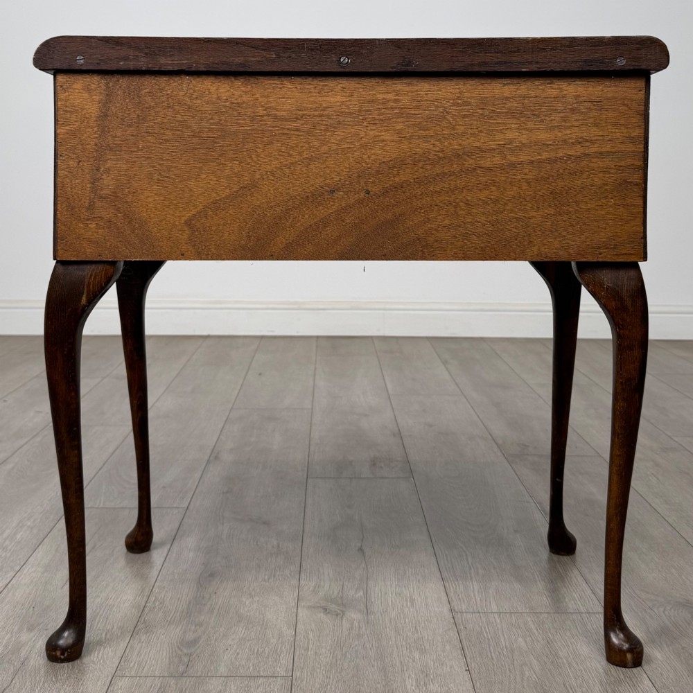An Edwardian oak side table featuring two front drawers with brass drop handles, a scalloped apron, and slender cabriole legs. View V