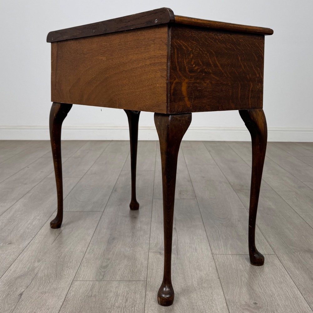 An Edwardian oak side table featuring two front drawers with brass drop handles, a scalloped apron, and slender cabriole legs. View VI