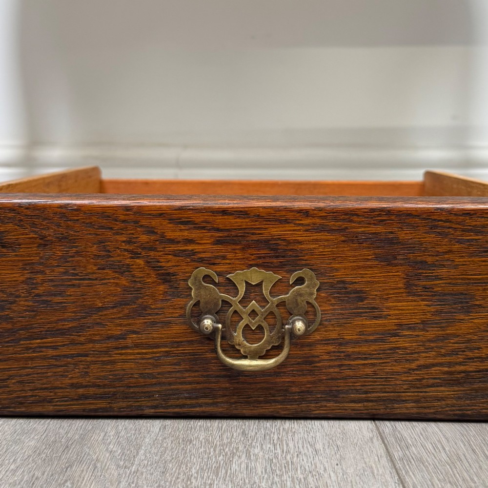 An Edwardian oak side table featuring two front drawers with brass drop handles, a scalloped apron, and slender cabriole legs. View XI
