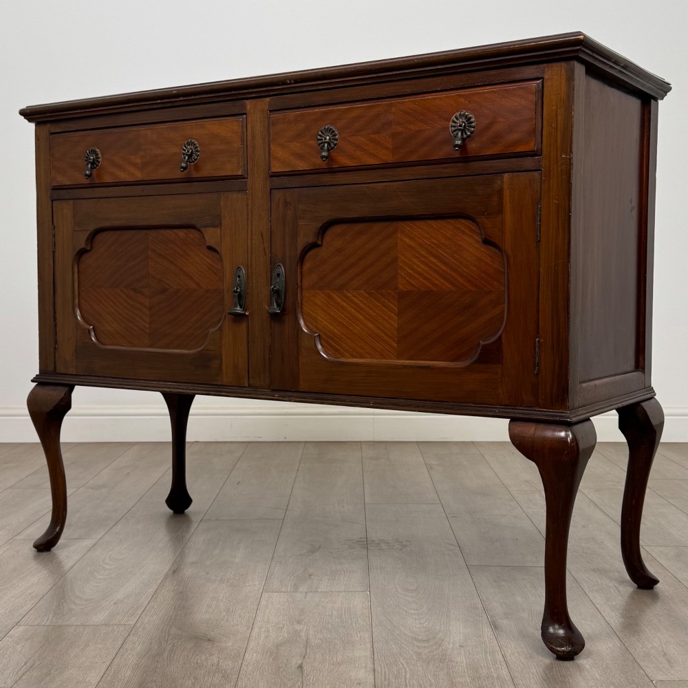 An Edwardian mahogany sideboard featuring two top drawers above a two-door cabinet supported on slender cabriole legs. View III