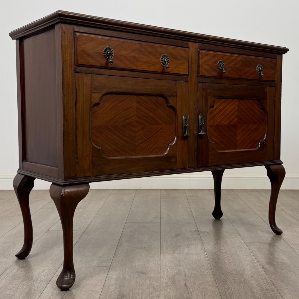 An Edwardian mahogany sideboard featuring two top drawers above a two-door cabinet supported on slender cabriole legs. View IX