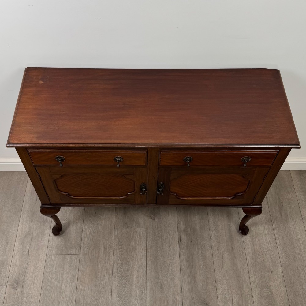 An Edwardian mahogany sideboard featuring two top drawers above a two-door cabinet supported on slender cabriole legs. View X