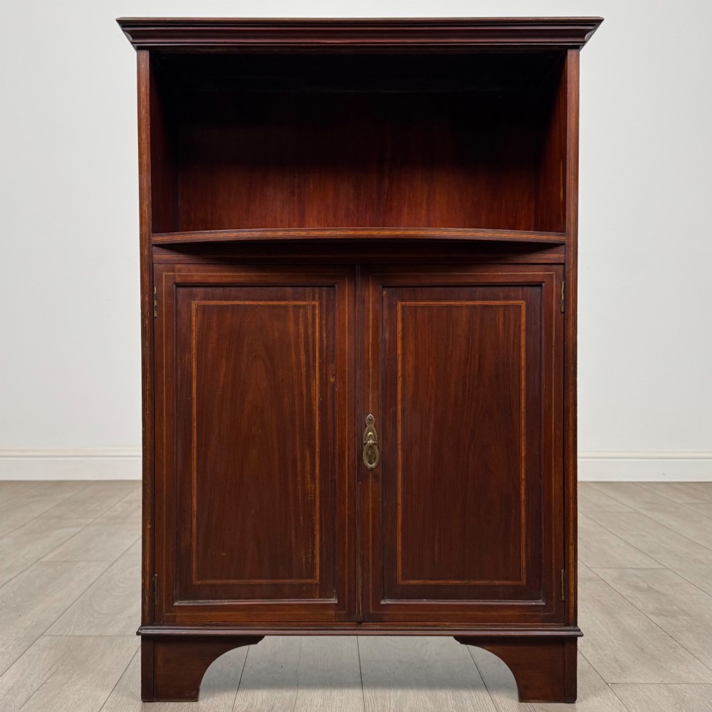 An Edwardian dark mahogany cabinet with an open upper shelf, two lower inlaid cupboard doors, and shaped bracket feet. View II
