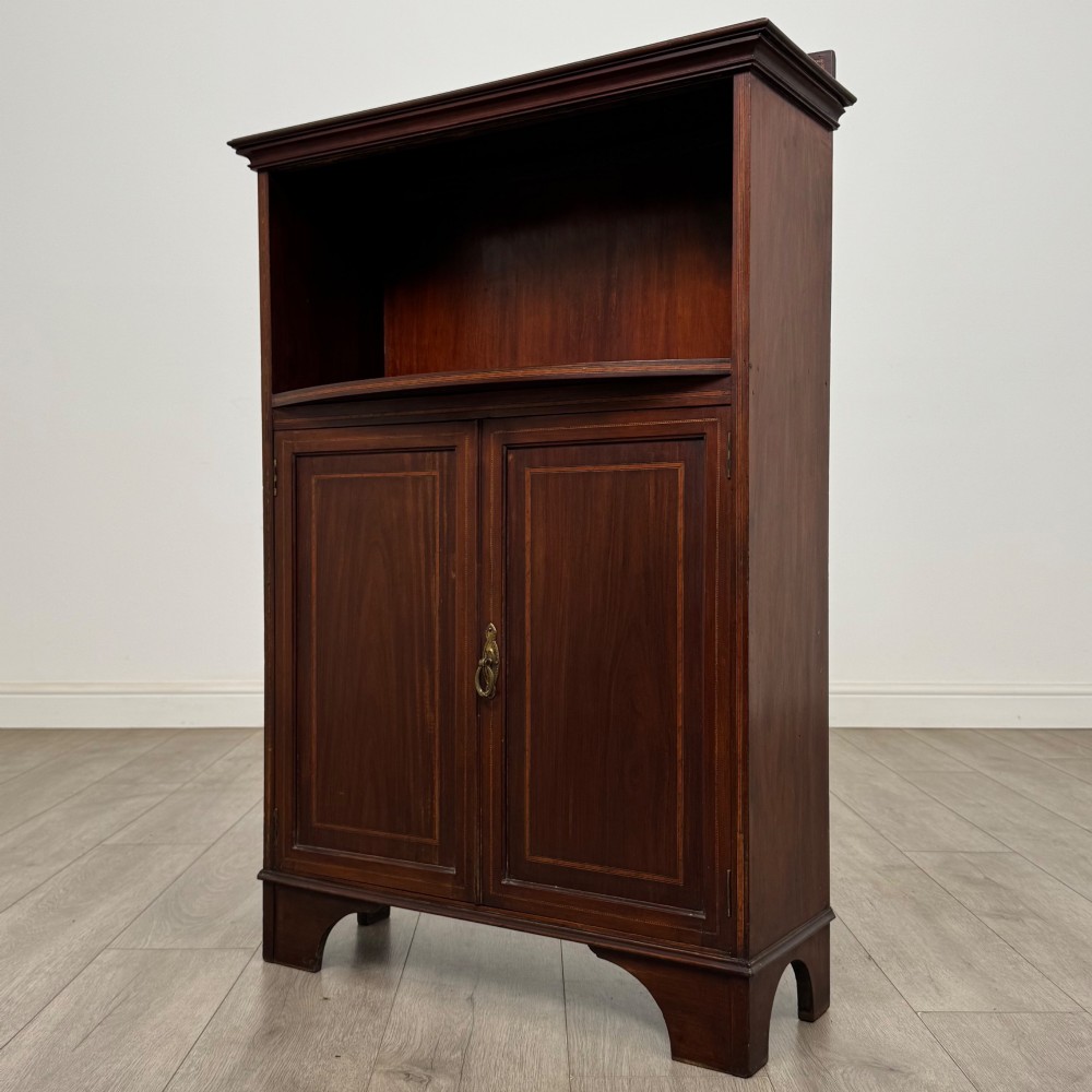 An Edwardian dark mahogany cabinet with an open upper shelf, two lower inlaid cupboard doors, and shaped bracket feet. View IV