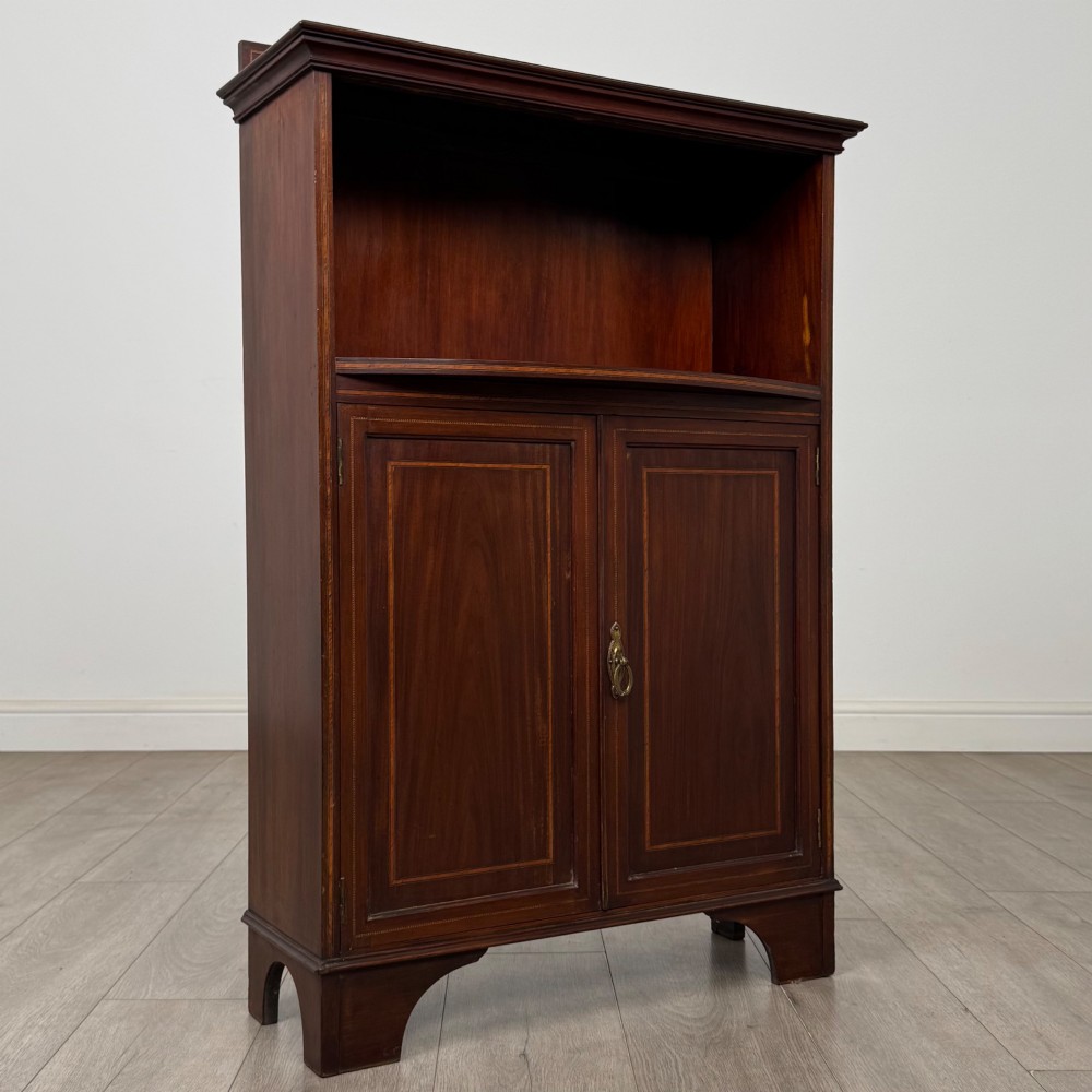 An Edwardian dark mahogany cabinet with an open upper shelf, two lower inlaid cupboard doors, and shaped bracket feet. View X