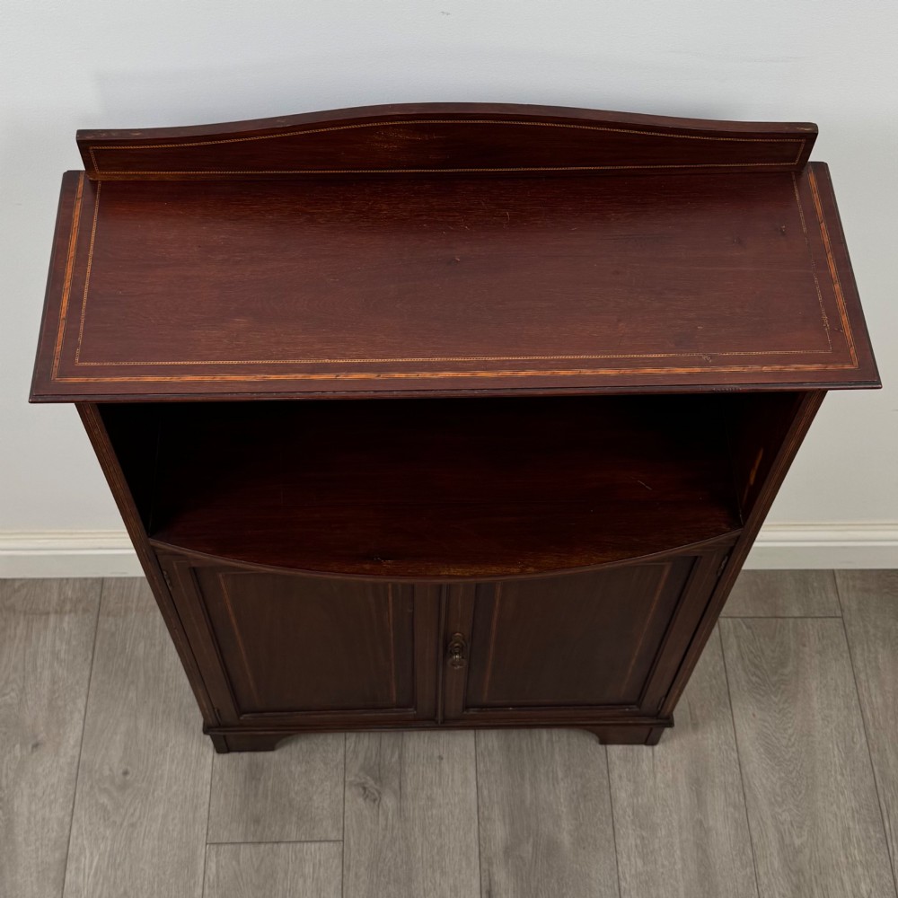 An Edwardian dark mahogany cabinet with an open upper shelf, two lower inlaid cupboard doors, and shaped bracket feet. View XI