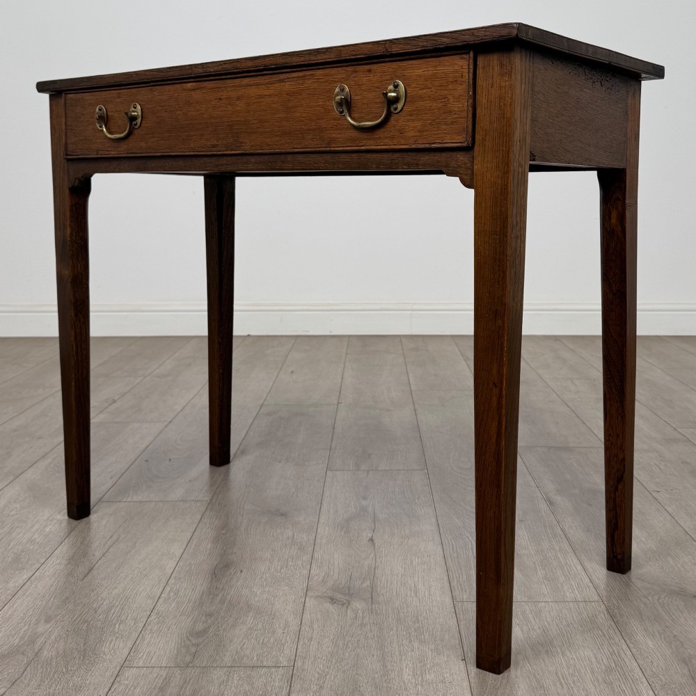 An 18th-century Georgian oak writing table with a full-width frieze drawer, two brass handles, and four square tapered legs. View II