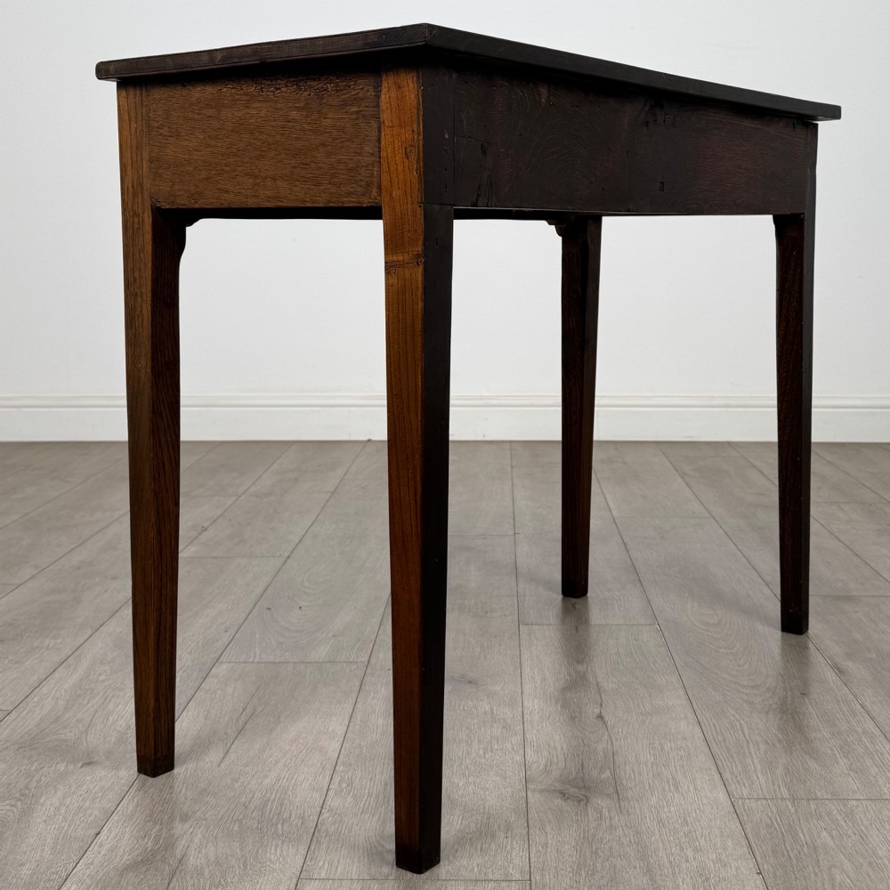 An 18th-century Georgian oak writing table with a full-width frieze drawer, two brass handles, and four square tapered legs. View IV