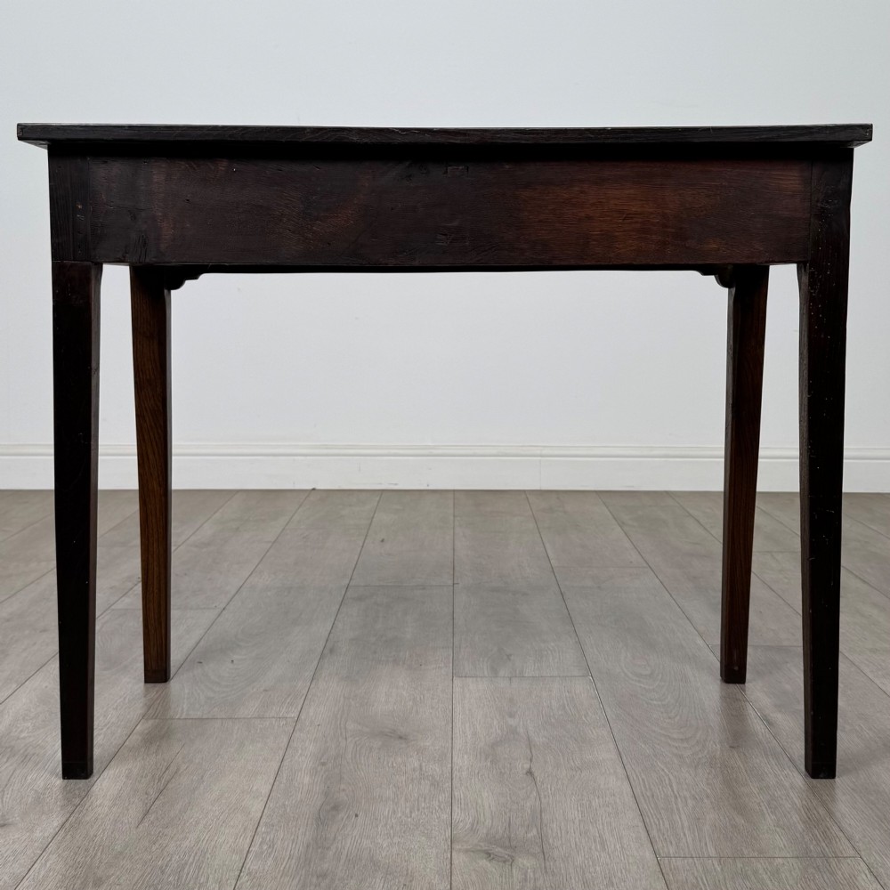 An 18th-century Georgian oak writing table with a full-width frieze drawer, two brass handles, and four square tapered legs. View V