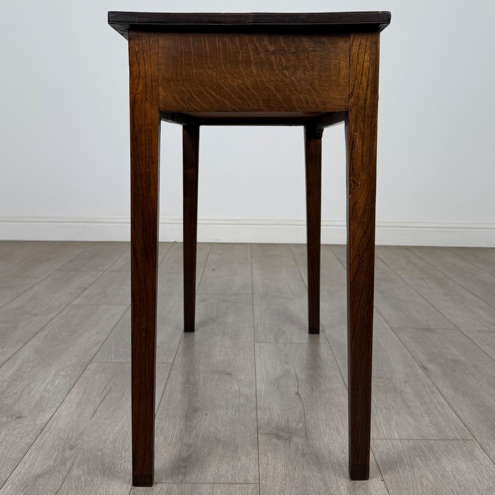 An 18th-century Georgian oak writing table with a full-width frieze drawer, two brass handles, and four square tapered legs. View VII