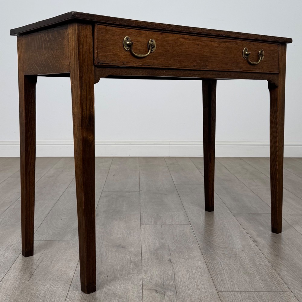 An 18th-century Georgian oak writing table with a full-width frieze drawer, two brass handles, and four square tapered legs. View VIII