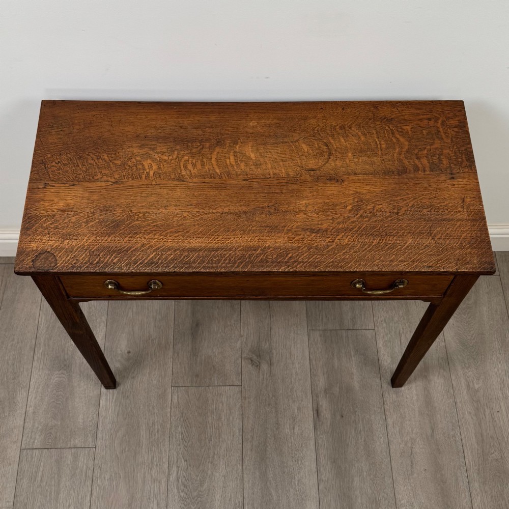 An 18th-century Georgian oak writing table with a full-width frieze drawer, two brass handles, and four square tapered legs. View IX
