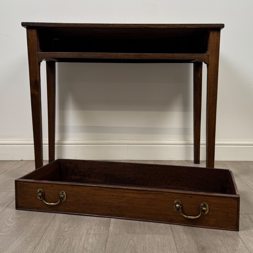 An 18th-century Georgian oak writing table with a full-width frieze drawer, two brass handles, and four square tapered legs. View X