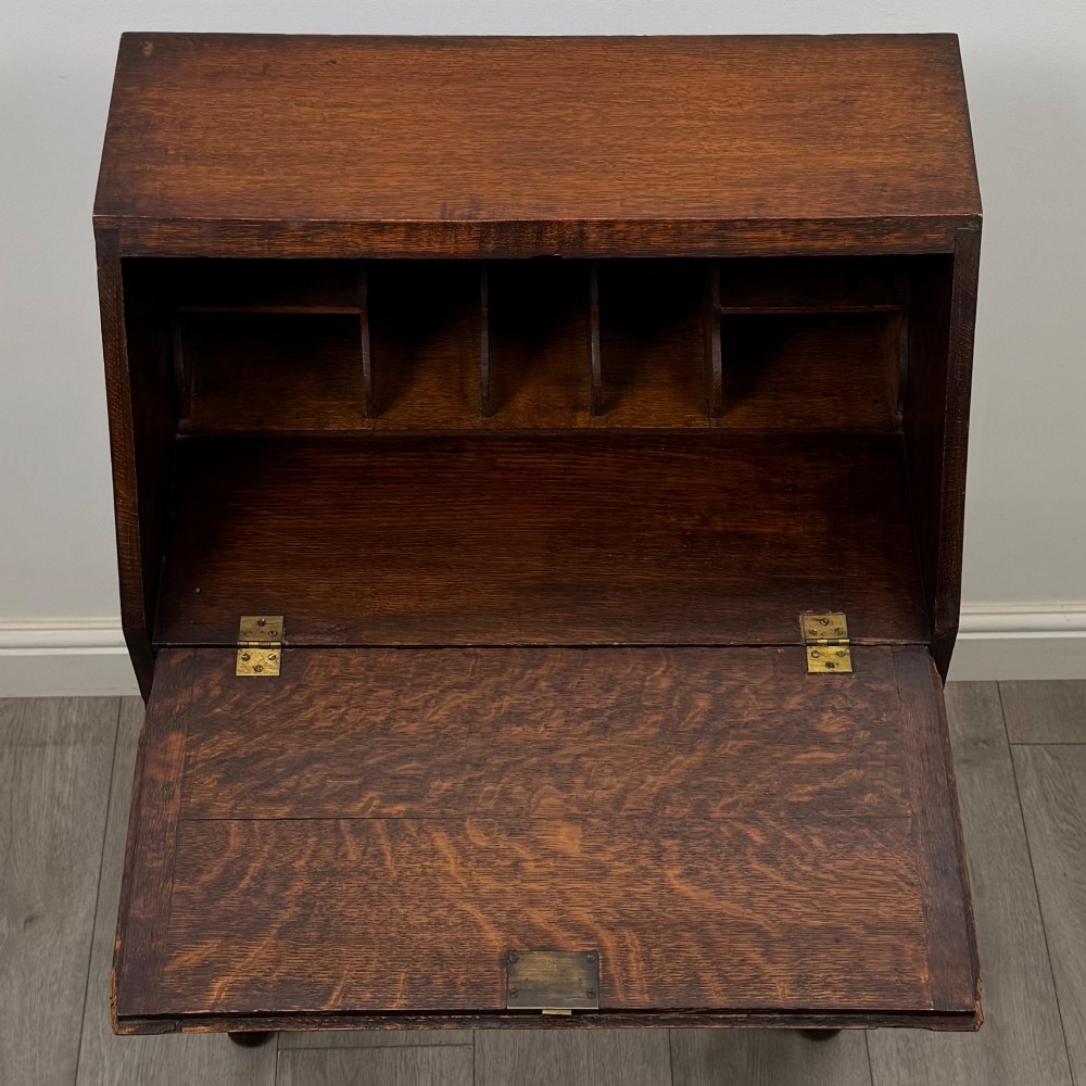 A dark oak Jacobean style bureau featuring a slanted drop-front lid, geometric moulding, a single drawer with teardrop handles, and turned legs with low stretchers. View XI