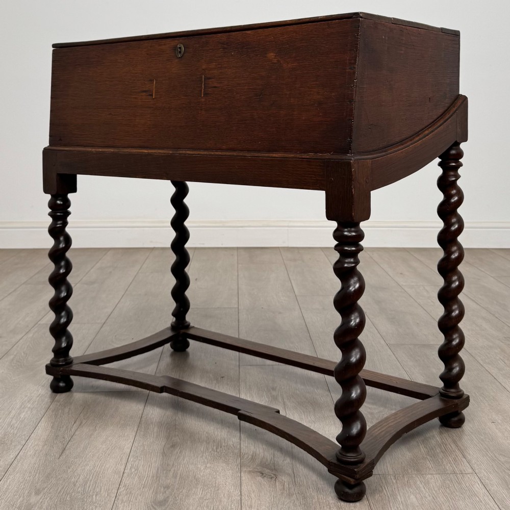 A 19th-century dark oak box on a wooden stand featuring four spiral barley twist legs and a central brass keyhole escutcheon. View II