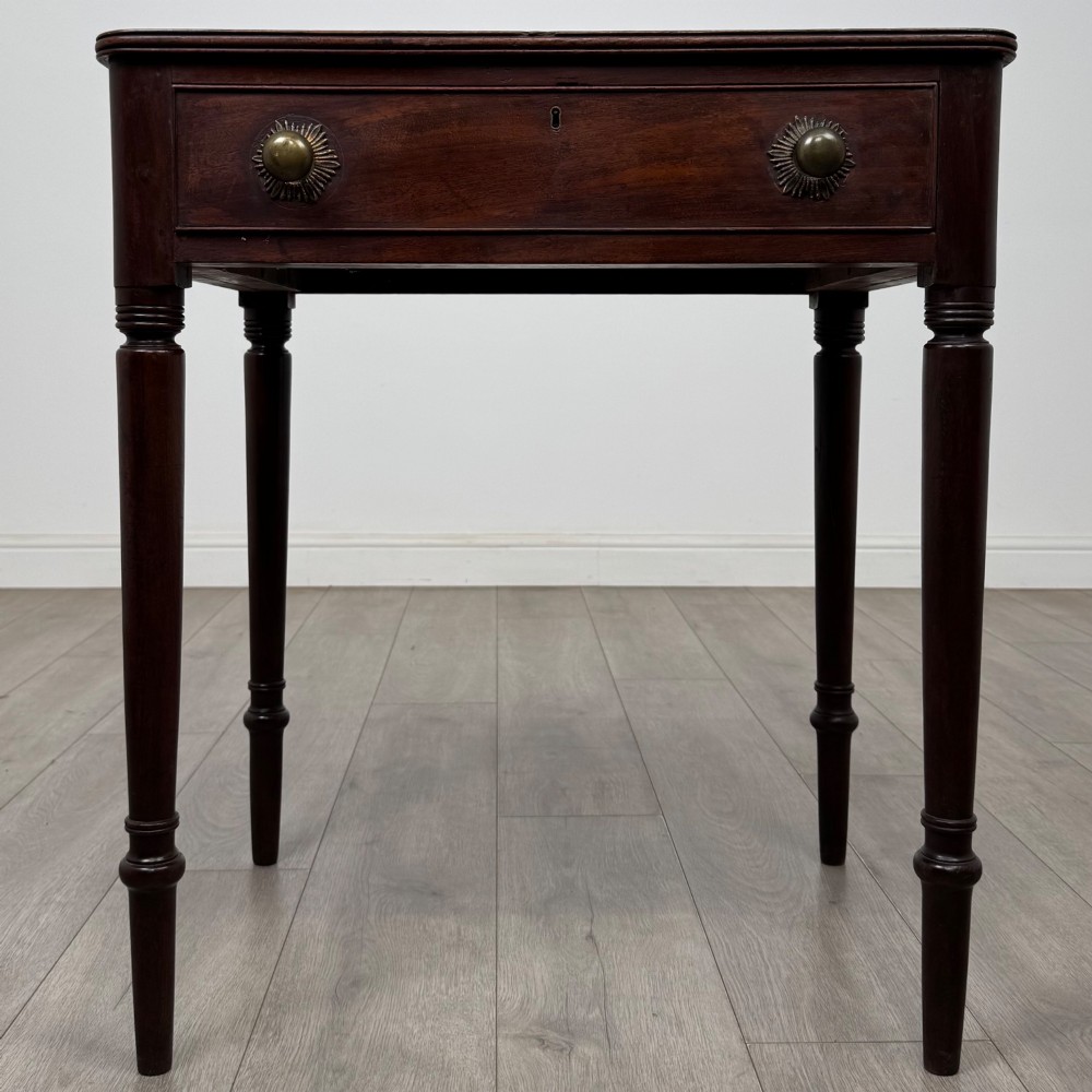 An antique dark mahogany Georgian side table featuring a single drawer with two brass sunburst knobs and slender turned legs.