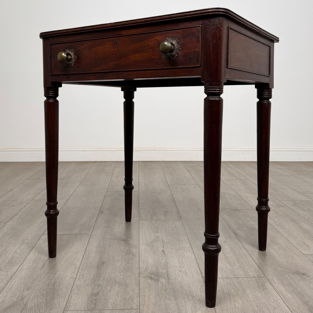 An antique dark mahogany Georgian side table featuring a single drawer with two brass sunburst knobs and slender turned legs. View II