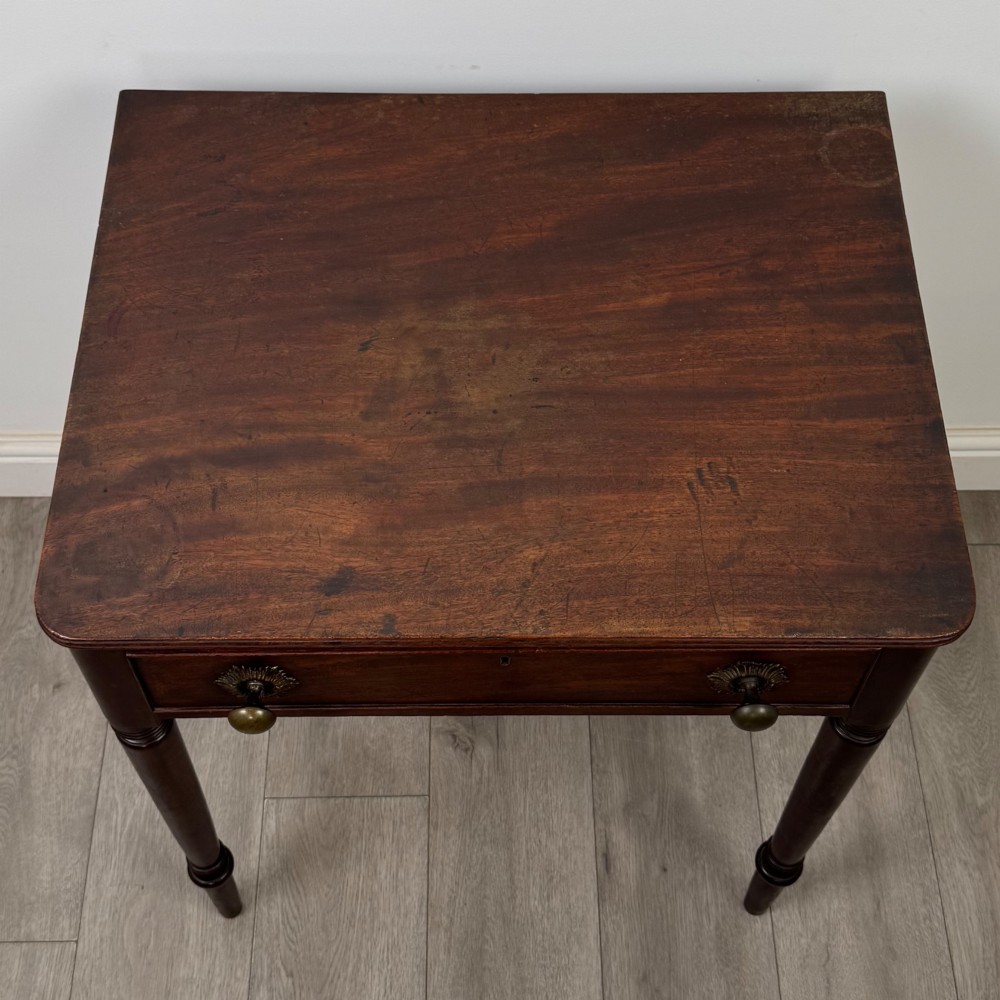 An antique dark mahogany Georgian side table featuring a single drawer with two brass sunburst knobs and slender turned legs. View IX